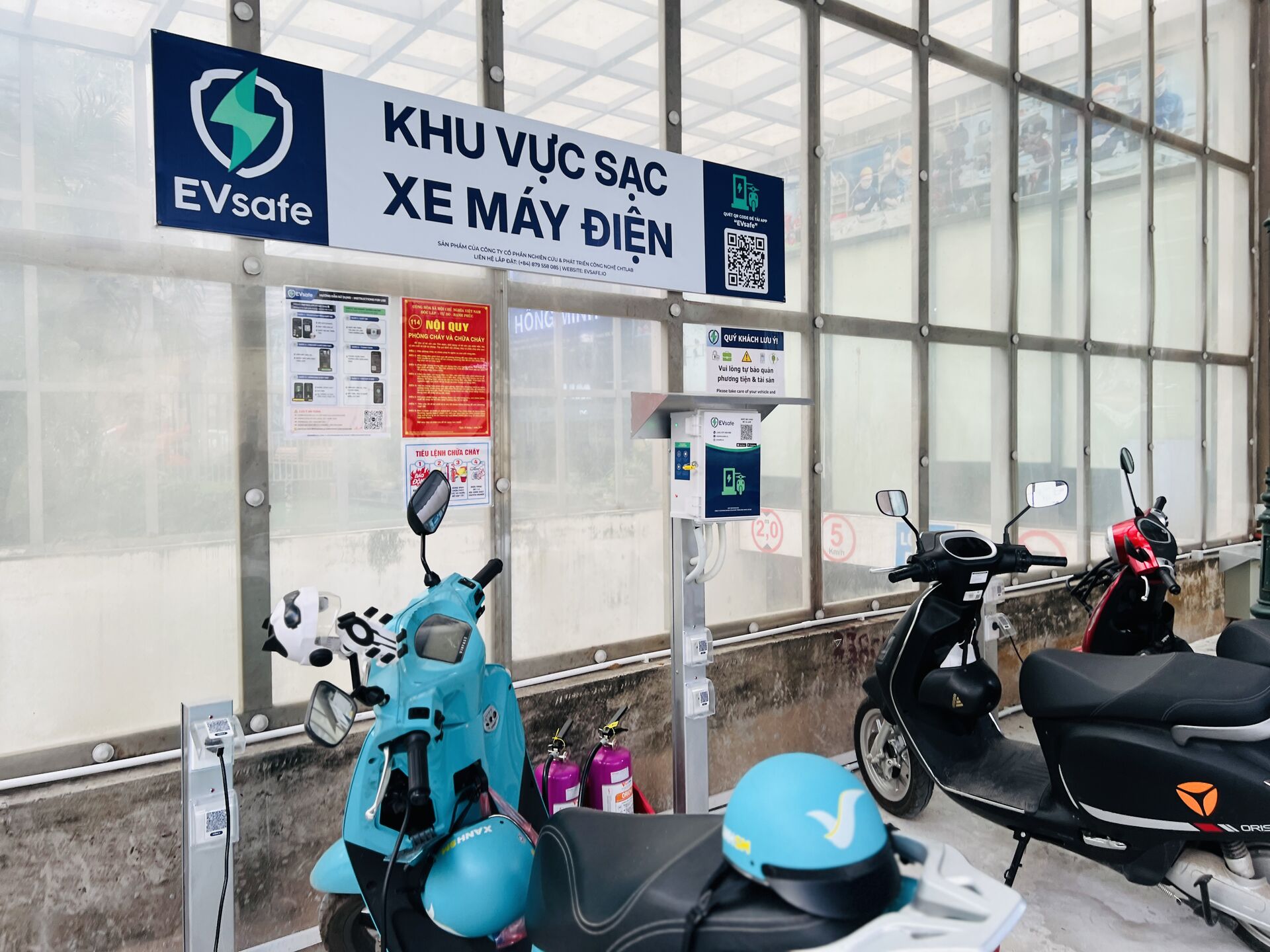 Trạm sạc xe máy điện hiện đại lắp đặt trong tòa nhà chung cư mini với nhiều điểm sạc, không gian đô thị, ánh sáng tự nhiên rõ nét