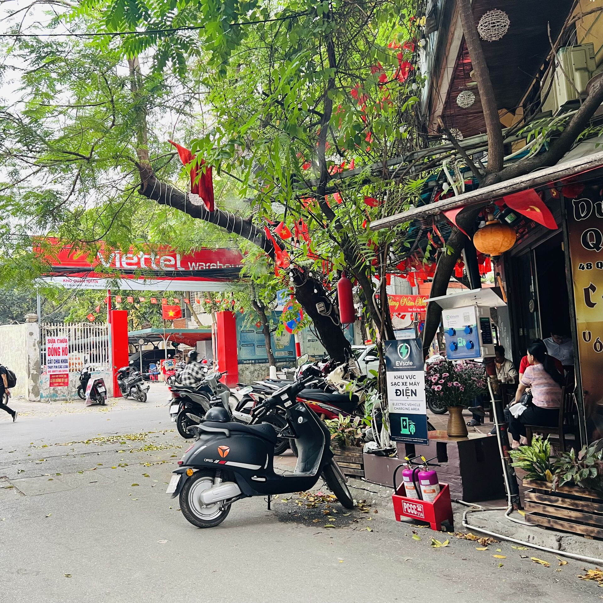 Trạm sạc xe máy điện hiện đại tại quận Cầu Giấy với nhiều cổng sạc, được đặt trong khu vực dân cư sầm uất với kiến trúc đô thị hiện đại