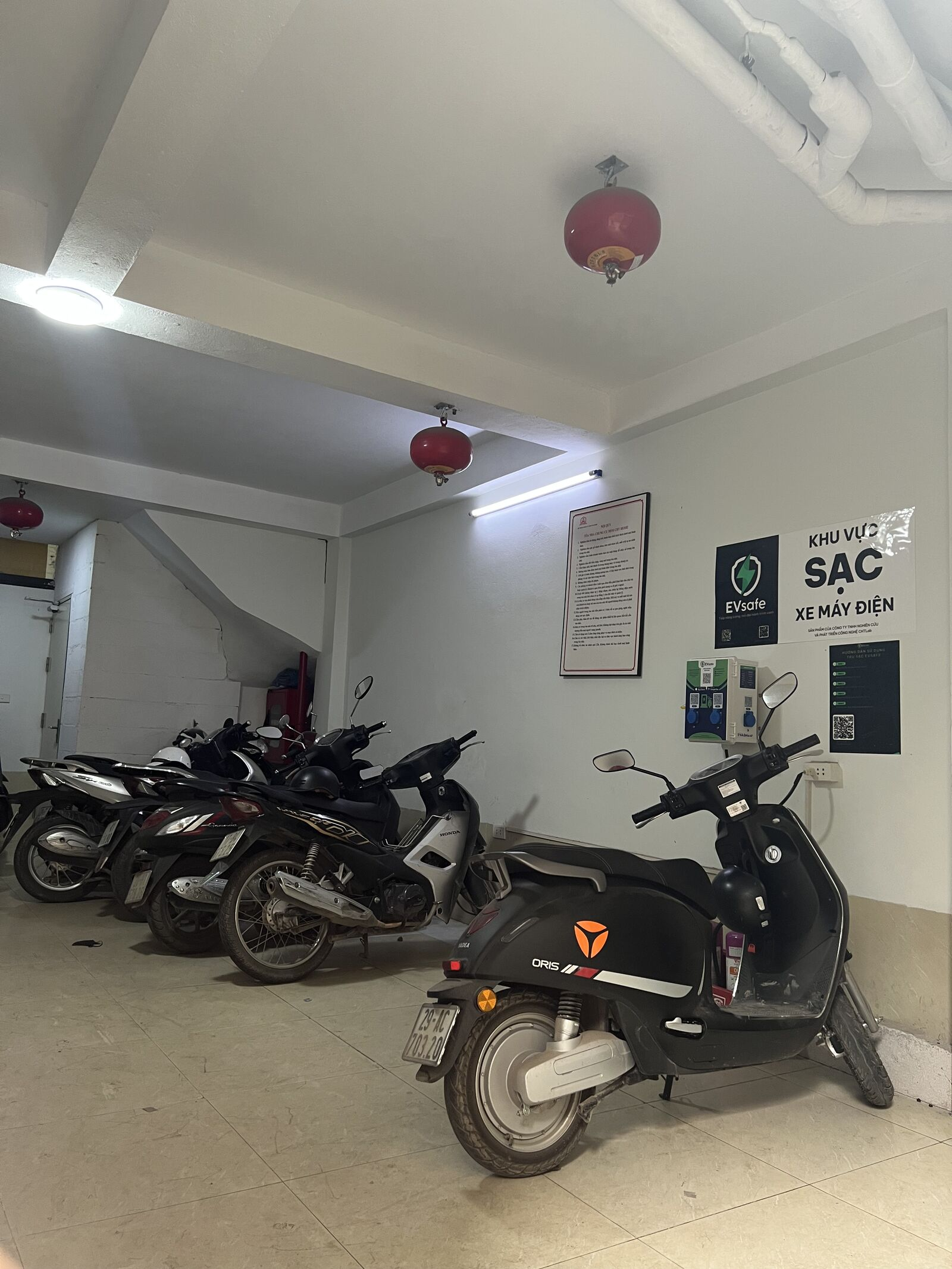 Khu vực sạc xe máy điện EVsafe tại hầm xe chung cư mini CHT Home Tân Triều, Hà Nội — có bình chữa cháy và nội quy PCCC